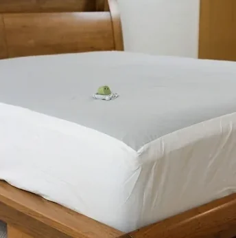 Corner of a white grounding sheet fitted on a bed with its grounding connector