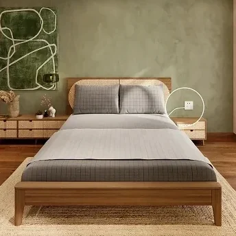 A grounding sheet on a made bed in a sage green bedroom