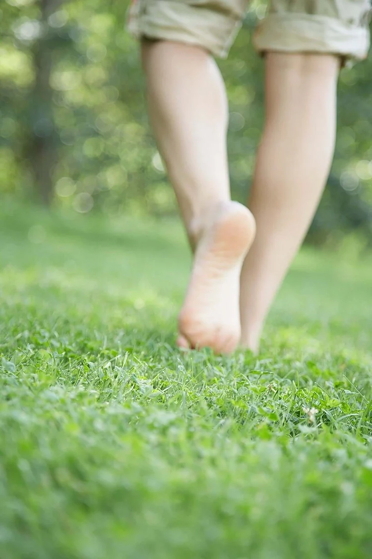 Bare feet walking on grass, the natural form of grounding or earthing